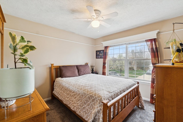 bedroom featuring dark colored carpet, a textured ceiling, baseboards, and ceiling fan