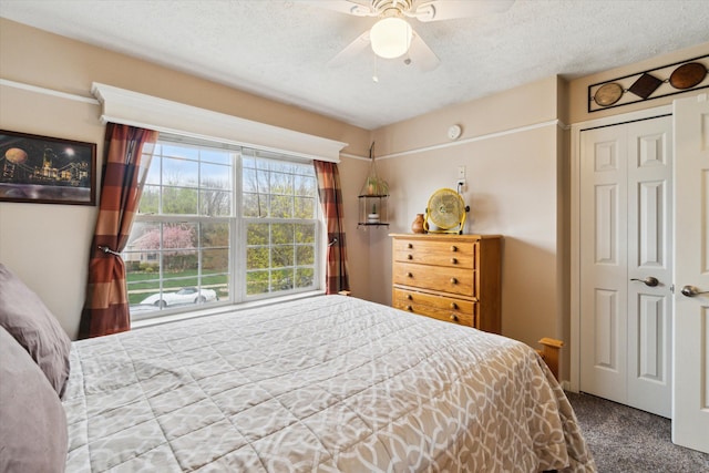 bedroom with ceiling fan, carpet flooring, and a textured ceiling