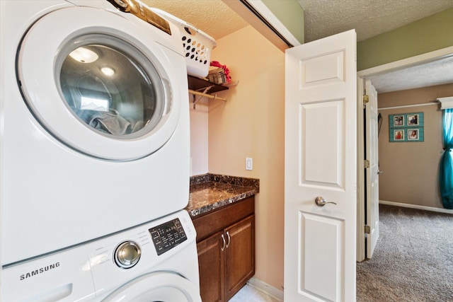 laundry area with laundry area, stacked washer and dryer, light carpet, baseboards, and a textured ceiling