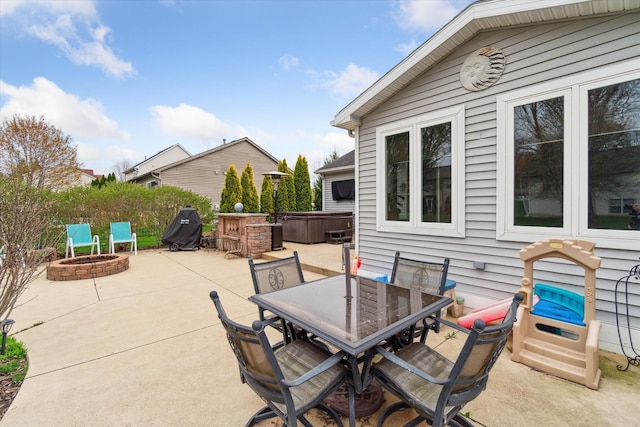 view of patio / terrace with a hot tub, outdoor dining space, and an outdoor fire pit