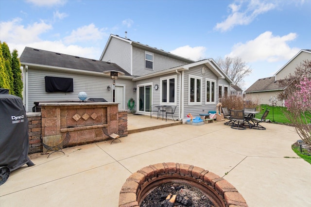 rear view of house with outdoor dining space, an outdoor fire pit, and a patio area