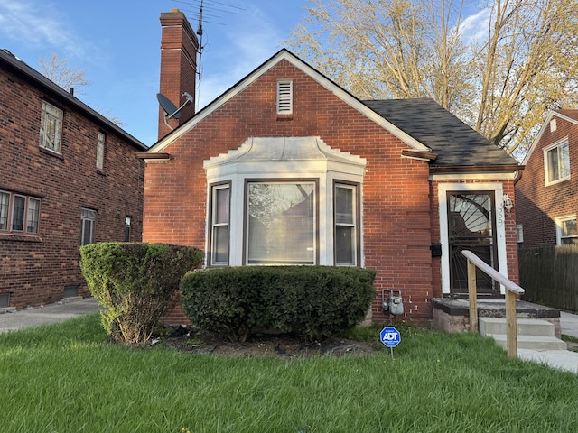 5566 Somerset Ave, Detroit, MI 48224 - view of front of house with brick siding, a front lawn, a shingled roof, and a chimney