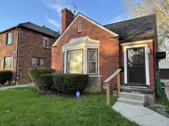 5566 Somerset Ave, Detroit, MI 48224 - view of front facade with roof with shingles, a chimney, a front yard, and brick siding