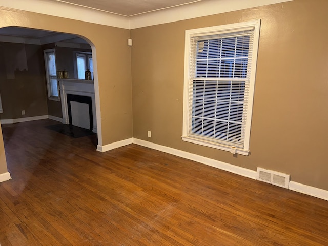 5566 Somerset Ave, Detroit, MI 48224 - empty room featuring baseboards, a fireplace with flush hearth, visible vents, arched walkways, and wood finished floors