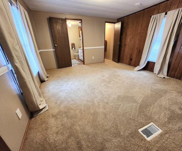 unfurnished bedroom featuring visible vents, multiple windows, and carpet