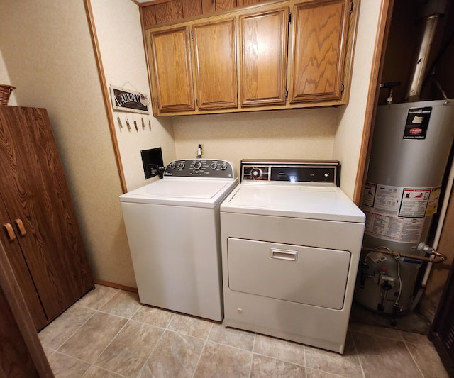 clothes washing area featuring washing machine and clothes dryer, gas water heater, and cabinet space