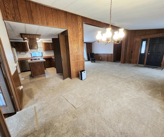 unfurnished dining area with wood walls, light colored carpet, and a chandelier