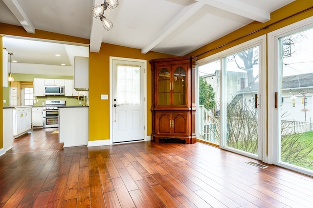33 N Church St, Ortonville, MI 48462 - entrance foyer with visible vents, beam ceiling, and dark wood-type flooring