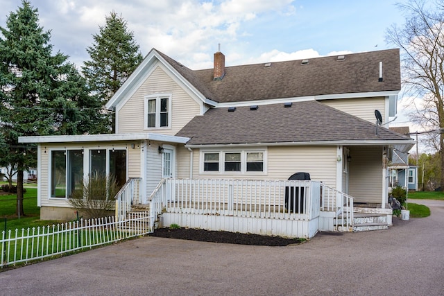 33 N Church St, Ortonville, MI 48462 - back of house with a chimney, fence, a sunroom, and roof with shingles