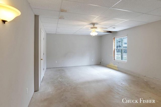 empty room with a paneled ceiling, a ceiling fan, and unfinished concrete flooring