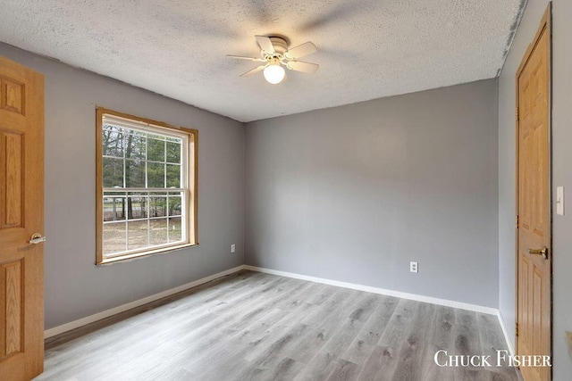 spare room with wood finished floors, a textured ceiling, and a ceiling fan