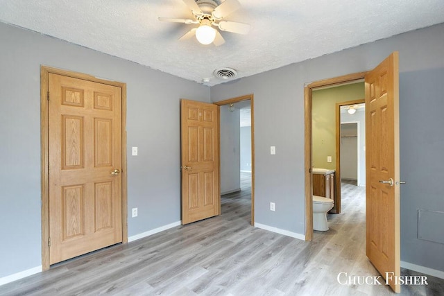 unfurnished bedroom featuring baseboards, visible vents, a textured ceiling, and light wood-style floors