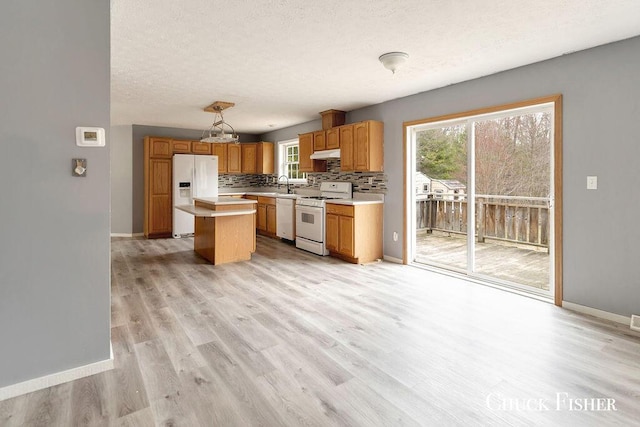 kitchen featuring light wood-style flooring, a sink, white appliances, light countertops, and under cabinet range hood