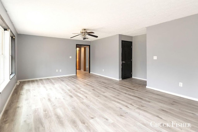 empty room with baseboards, a ceiling fan, and light wood finished floors