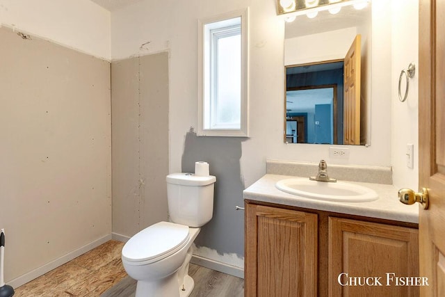 bathroom featuring wood finished floors, toilet, and vanity