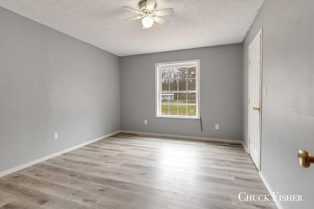 spare room with wood finished floors, a textured ceiling, baseboards, and ceiling fan