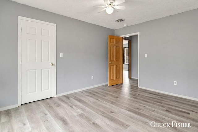 empty room with a ceiling fan, a textured ceiling, light wood-style flooring, baseboards, and visible vents