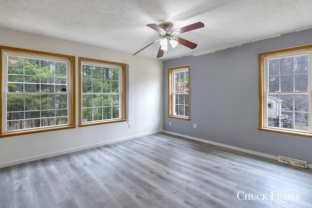 unfurnished room with wood finished floors, visible vents, a ceiling fan, baseboards, and a textured ceiling