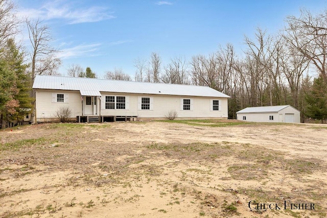 back of property featuring a garage, entry steps, metal roof, and an outdoor structure