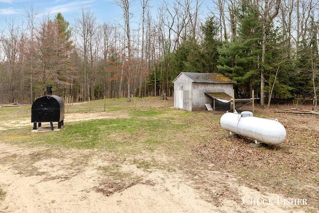 view of yard with an outdoor structure, heating fuel, and a view of trees