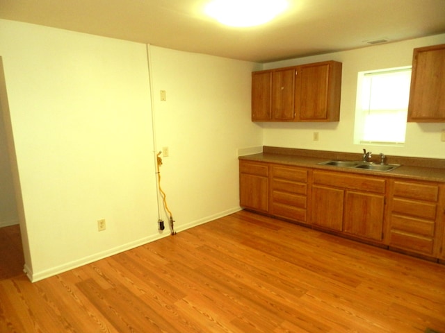 1187 Villa Ct, Benton Harbor, MI 49022 - kitchen with brown cabinetry, light wood-type flooring, visible vents, a sink, and baseboards