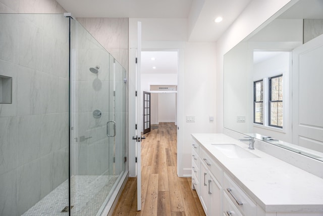 full bath with a stall shower, wood finished floors, vanity, and recessed lighting