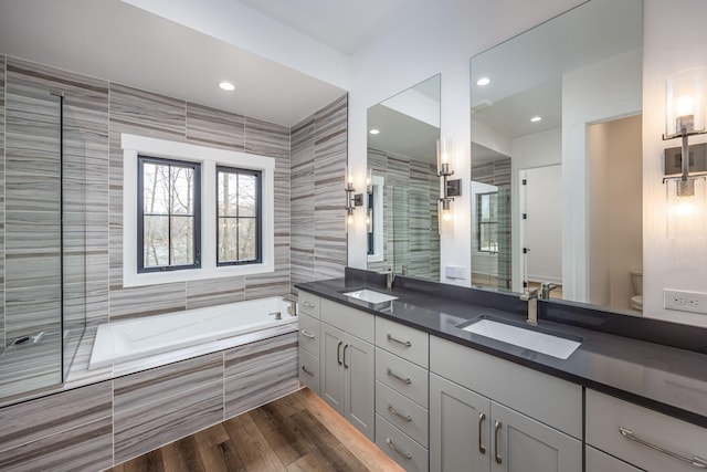 bathroom featuring a shower stall, a bath, toilet, a sink, and double vanity