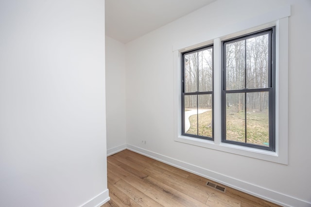 unfurnished room with light wood-style floors, baseboards, visible vents, and a wealth of natural light