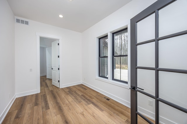 unfurnished room featuring visible vents, baseboards, and wood-type flooring