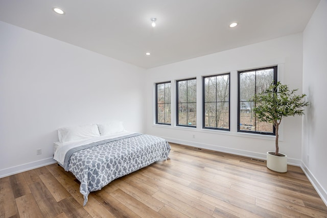 bedroom with wood finished floors, baseboards, multiple windows, and recessed lighting
