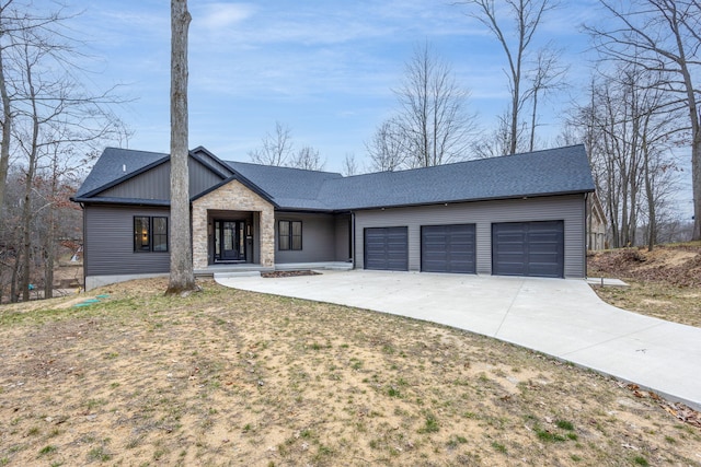 view of front facade with roof with shingles, concrete driveway, a garage, and stone siding