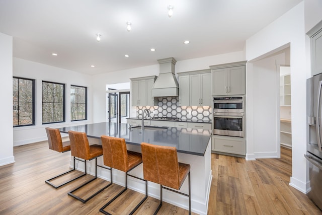kitchen with custom range hood, gray cabinetry, and appliances with stainless steel finishes