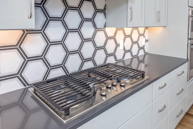 details with white cabinetry, backsplash, dark countertops, and stainless steel appliances