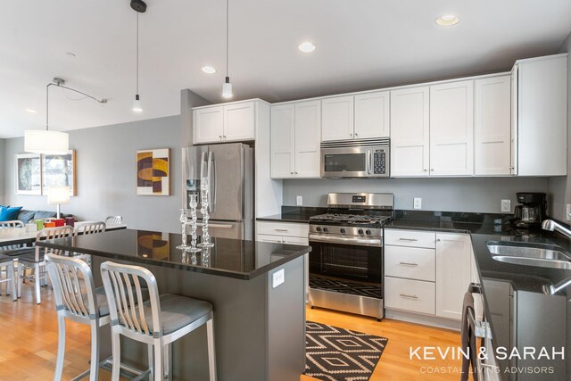 201C Outlook Dr Unit 8, Douglas, MI 49406 - kitchen featuring a sink, appliances with stainless steel finishes, a kitchen bar, white cabinetry, and light wood-style flooring