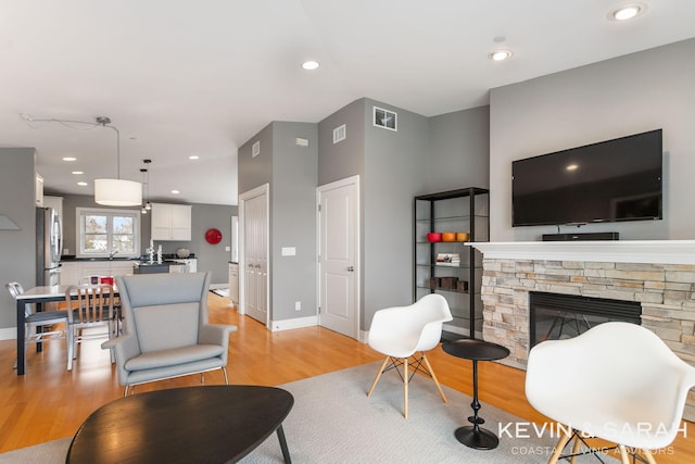 201C Outlook Dr Unit 8, Douglas, MI 49406 - living area featuring a stone fireplace, visible vents, baseboards, and light wood-style floors