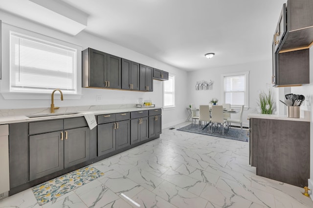 kitchen with baseboards, marble finish floor, a sink, and light stone countertops
