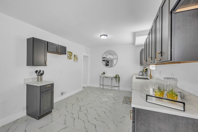 kitchen featuring light stone counters, marble finish floor, a sink, and visible vents