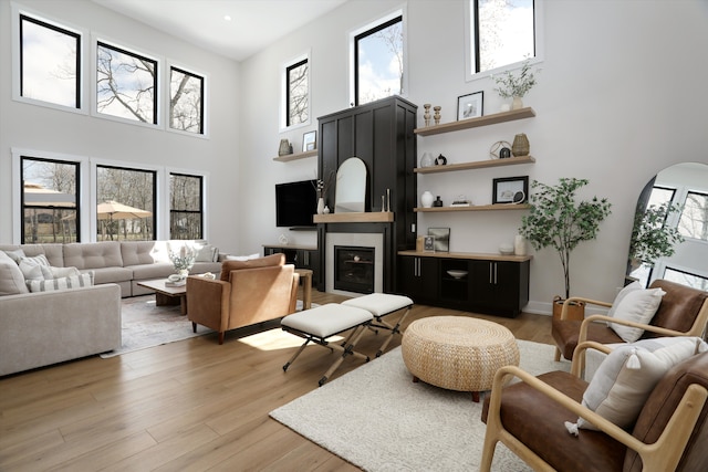 21907 Westcroft Dr, Grosse Ile, MI 48138 - living room with arched walkways, a towering ceiling, a glass covered fireplace, light wood finished floors, and baseboards