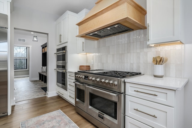 21907 Westcroft Dr, Grosse Ile, MI 48138 - kitchen featuring custom exhaust hood, visible vents, light countertops, light wood finished floors, and stainless steel appliances