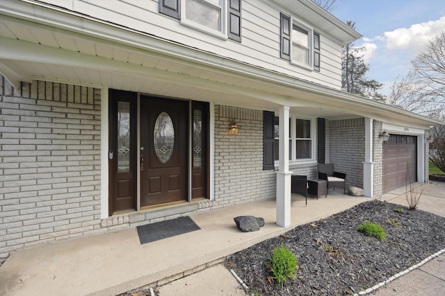 property entrance with brick siding, a porch, and driveway