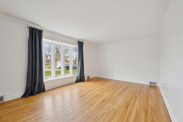 unfurnished room with crown molding, visible vents, baseboards, and light wood-style floors