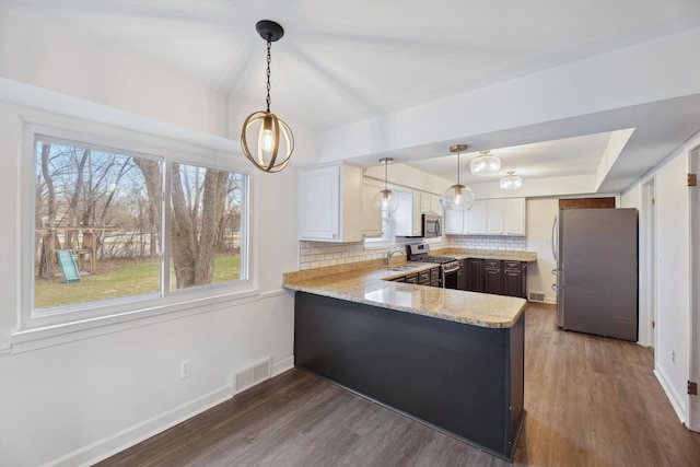 kitchen featuring dark wood-style flooring, visible vents, a peninsula, and stainless steel appliances