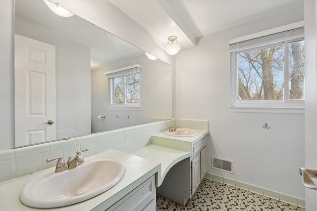 bathroom featuring double vanity, visible vents, baseboards, and a sink