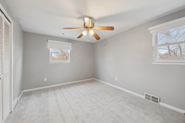 unfurnished bedroom featuring light carpet, visible vents, a closet, and baseboards