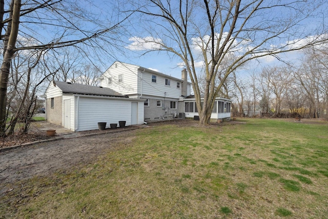 back of house with an outbuilding, a sunroom, a lawn, and a chimney