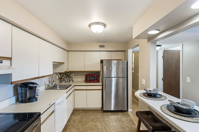 kitchen with freestanding refrigerator, a sink, dishwasher, light countertops, and under cabinet range hood