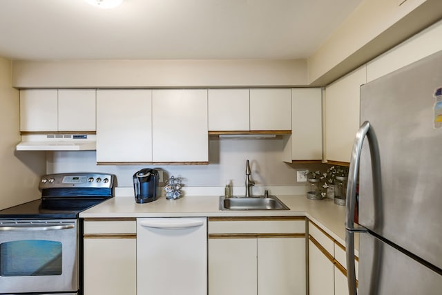 kitchen featuring appliances with stainless steel finishes, under cabinet range hood, a sink, light countertops, and white cabinetry