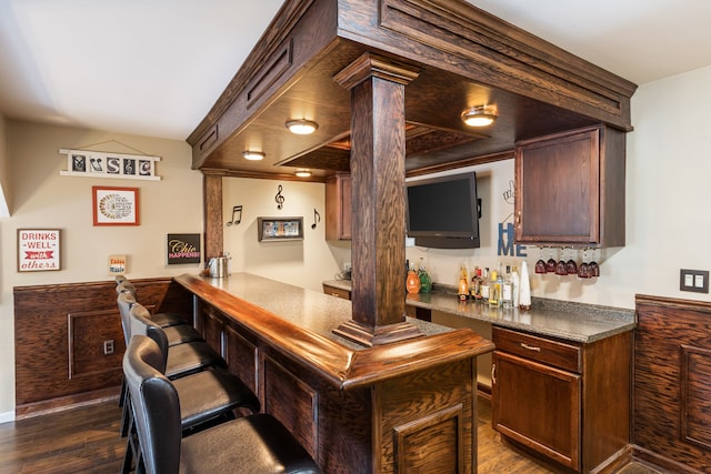 indoor dry bar with dark wood finished floors and decorative columns