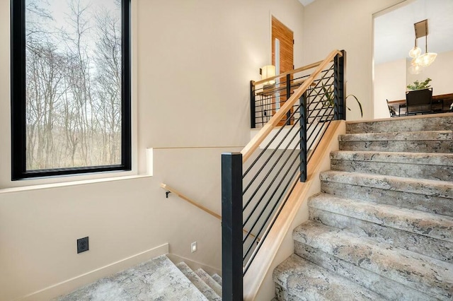 stairs with baseboards and a notable chandelier