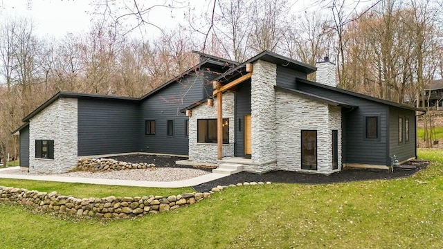 rear view of property featuring stone siding, a lawn, and a chimney